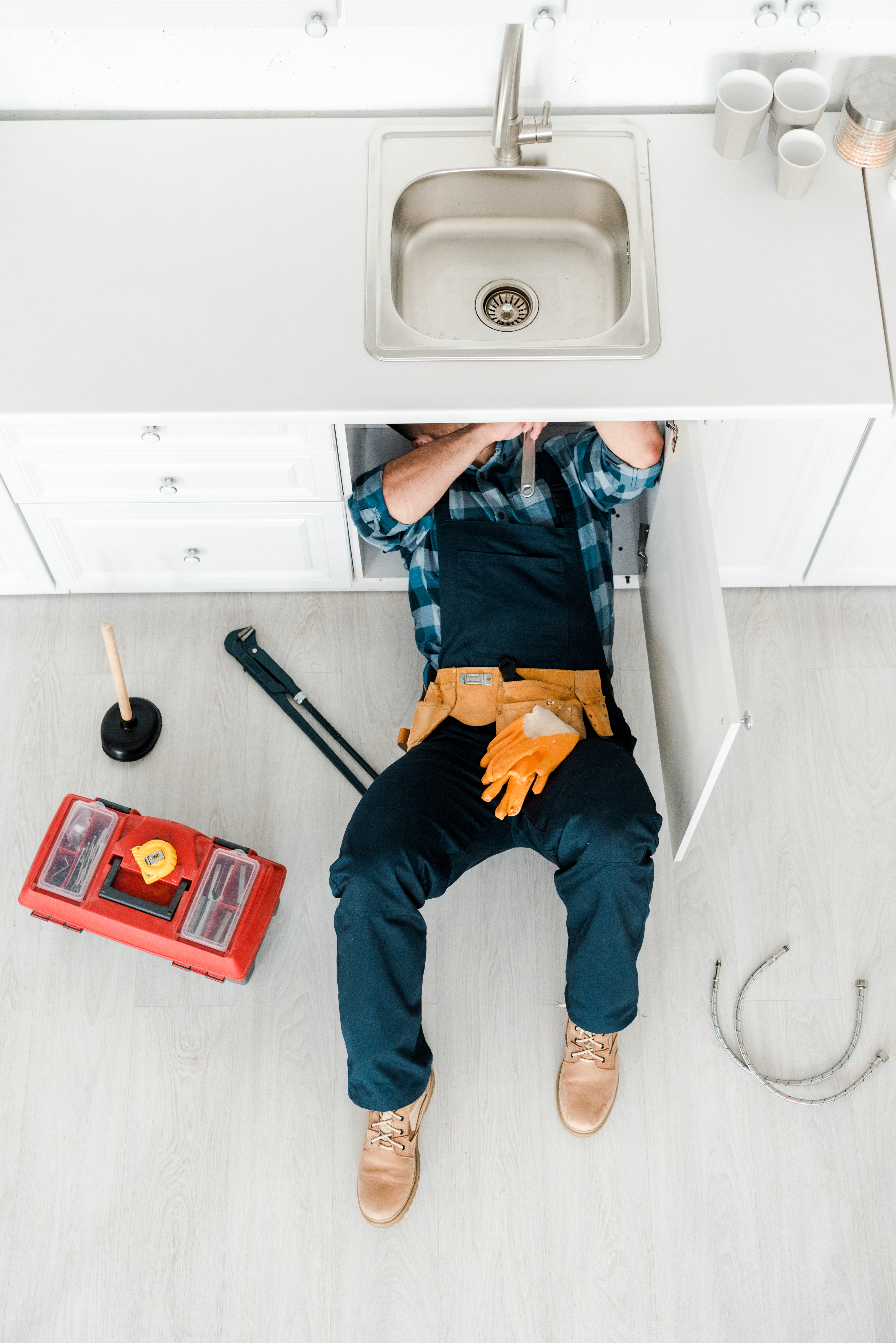 Plumber repairing pipework under a kitchen sink